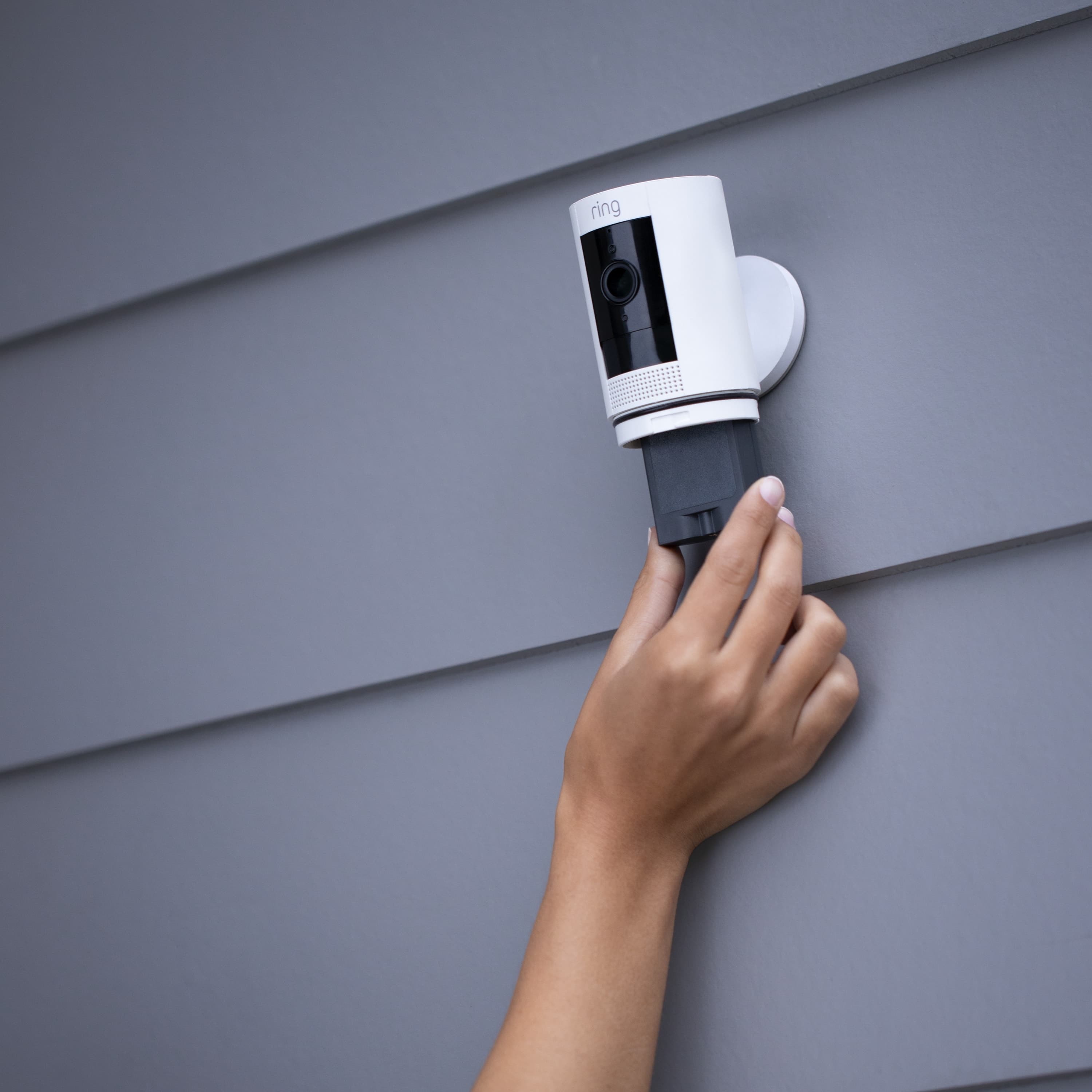 Quick Release Battery Pack - Person removing a Quick Release Battery Pack from a Ring security camera mounted on an exterior wall.