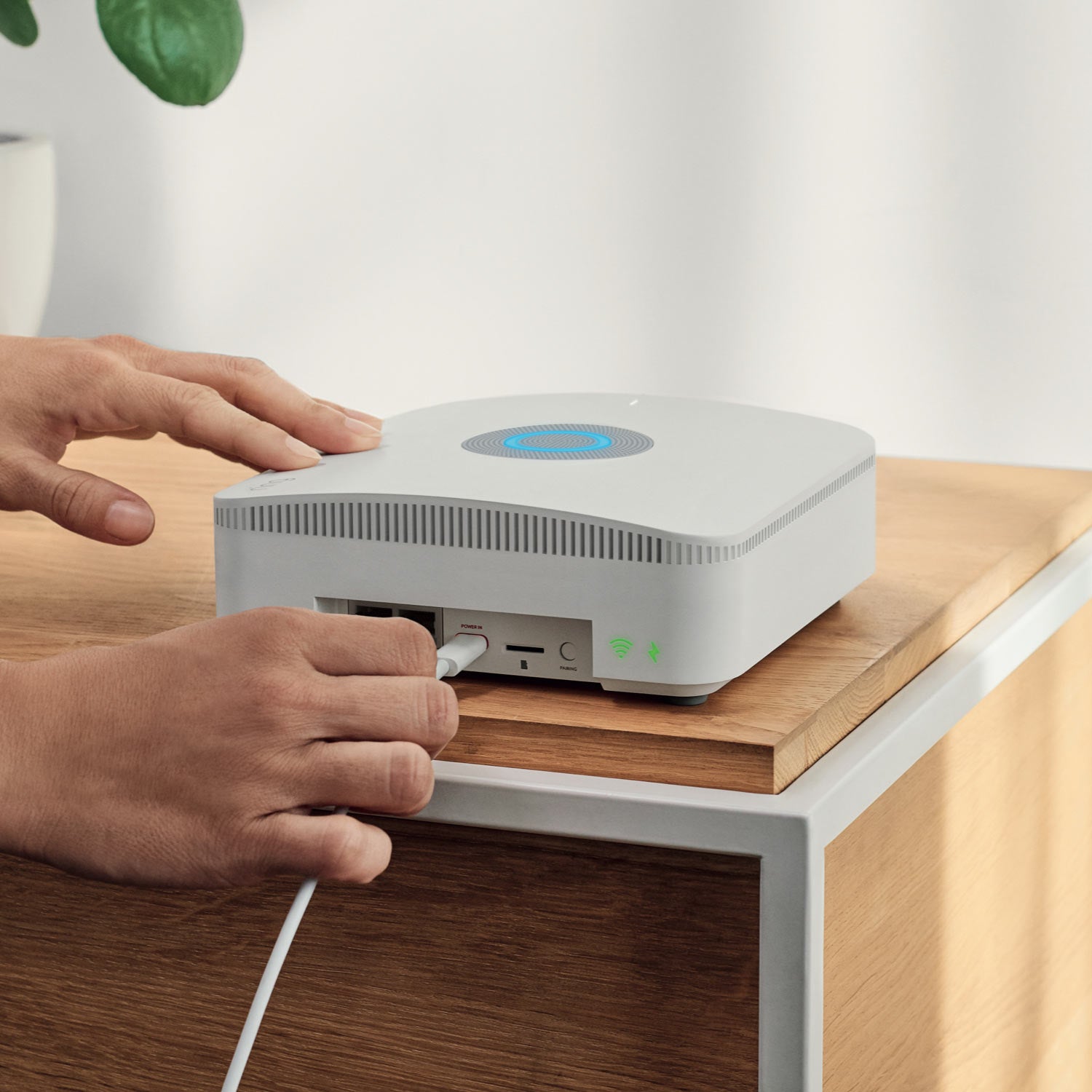 Alarm Pro Security Kit, 14-Piece (with built-in eero Wi-Fi 6 router) - Person plugging power cord into Ring Alarm Pro Base Station, with blue light glowing on top and ports visible.