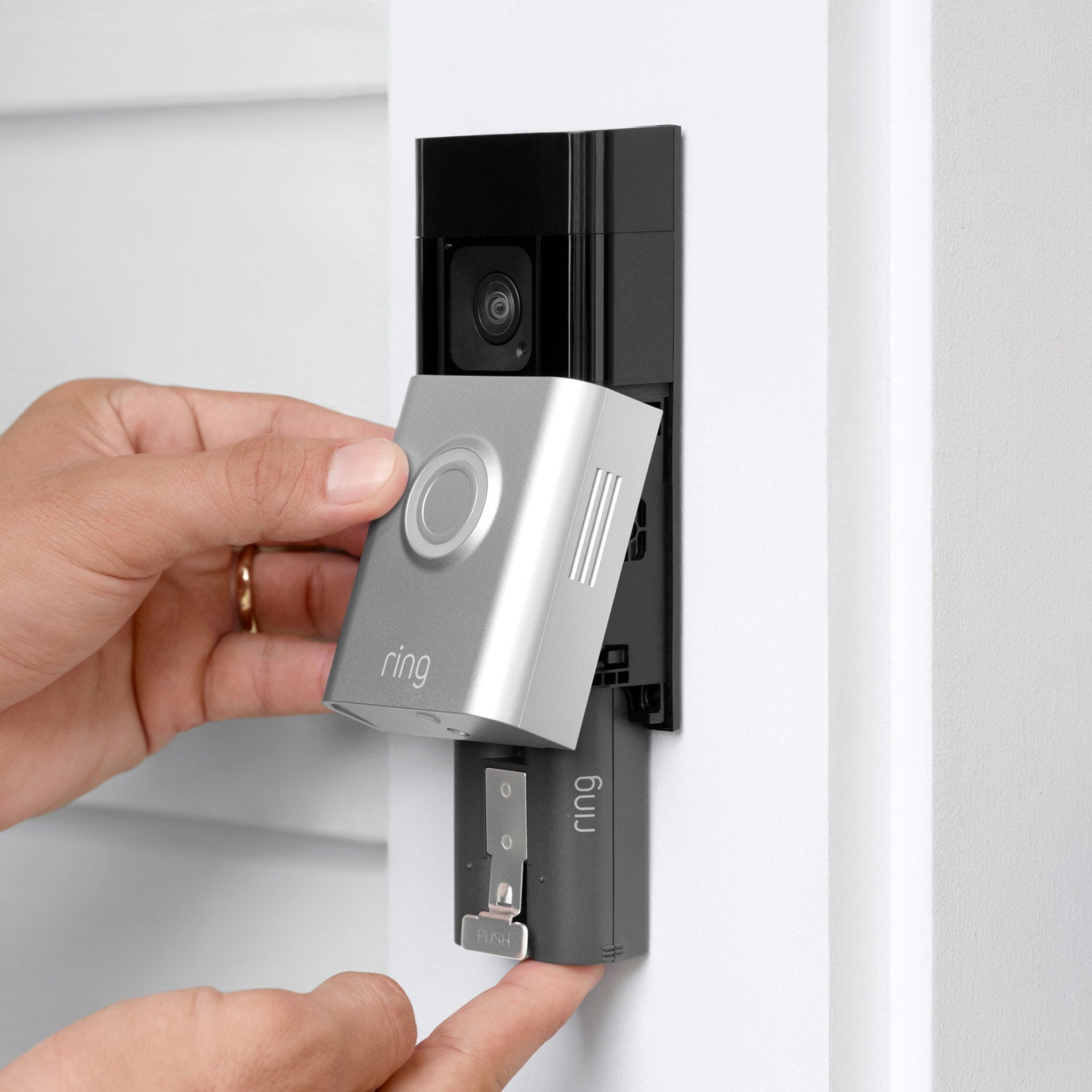 Battery Doorbell Plus - Hands removing Ring Battery Doorbell Plus faceplate on a door frame to access rechargeable quick-release battery pack.