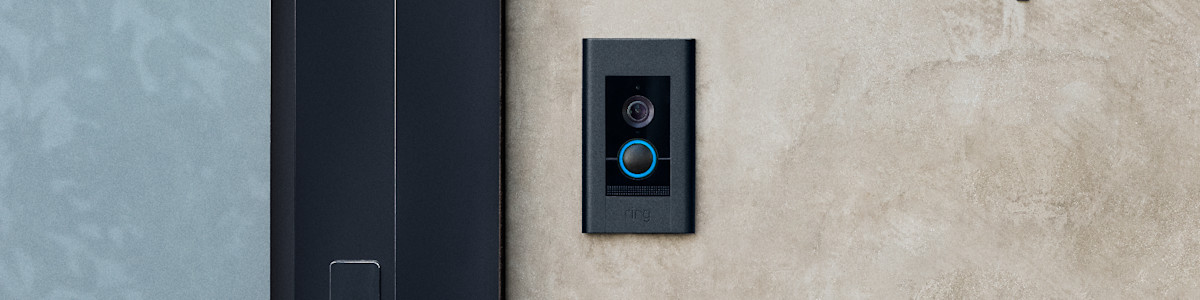 Black video doorbell Elite with blue ring light mounted on concrete wall