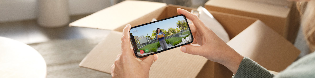 Hands holding phone displaying video call with delivery person on doorstep