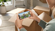 Hands holding phone displaying video call with delivery person on doorstep