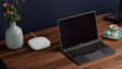 Laptop on wooden desk with coffee cup and grey vase with pink flowers